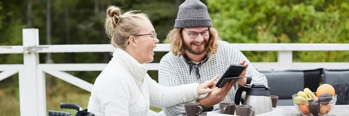 En mann i rullestol og en kvinne som sitter ved et bord.