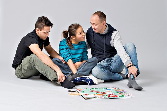 Liten gutt spiller monopol med to assistenter.